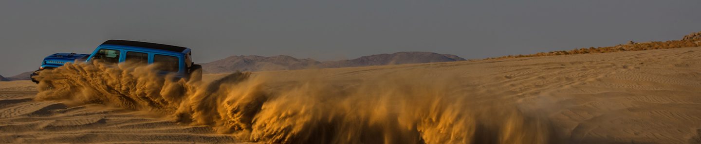 A large dust cloud coming from the wheels of the 2021 Jeep Wrangler Rubicon 392, nearly obscuring the vehicle.