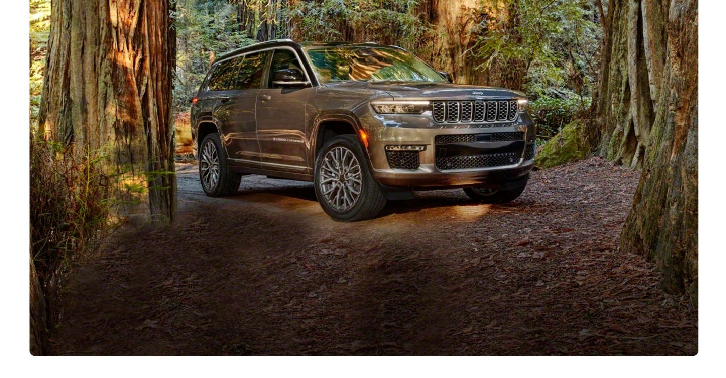 A three-quarter profile view of the 2021 Jeep Grand Cherokee L Summit parked on a forest trail.
