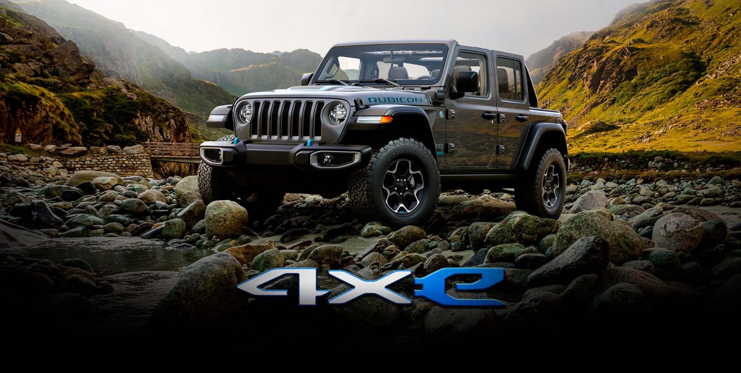 A 2022 Jeep Wrangler Rubicon 4xe parked on a rocky plateau, surrounded by mountains.